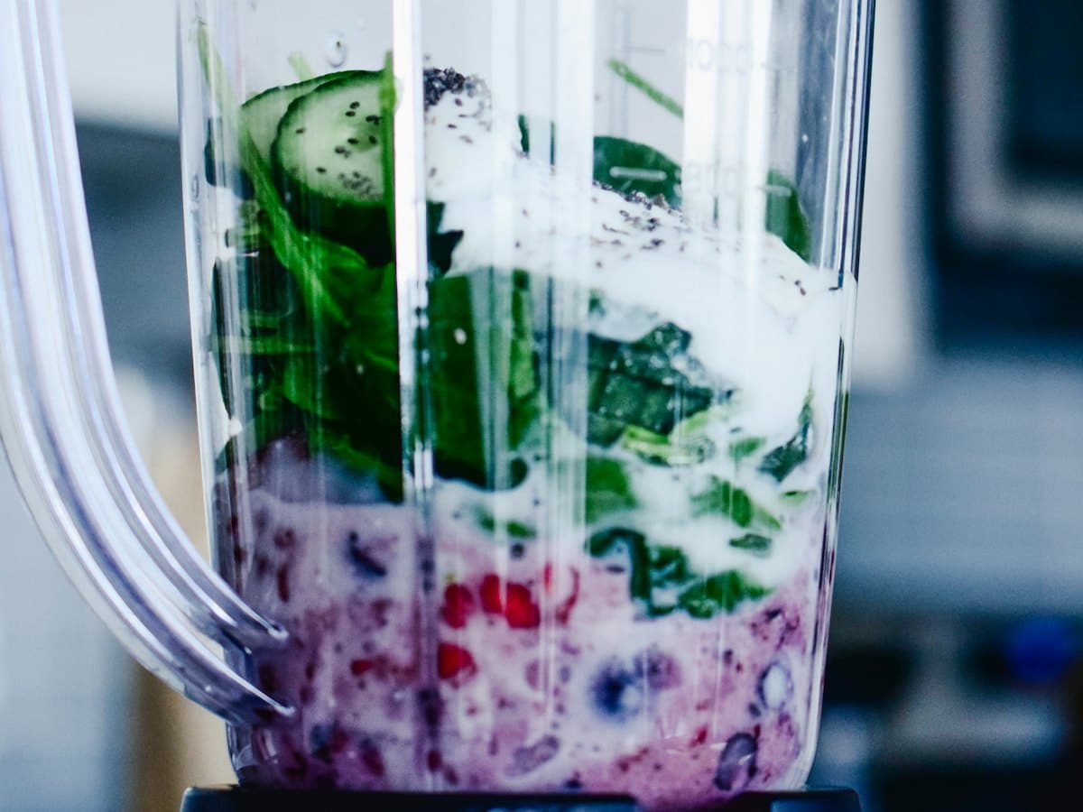 A mixer jar full of fruit and vegetables