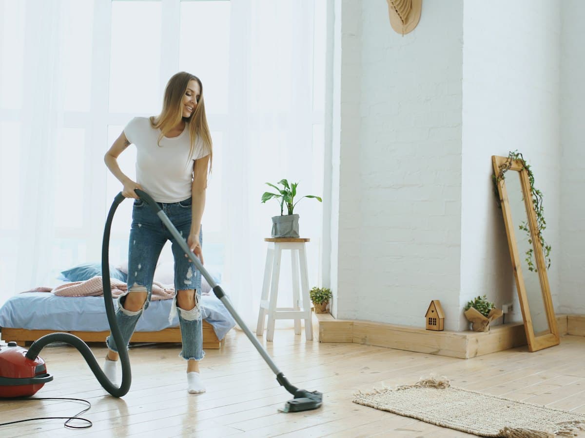 A woman cleaning the floor with a vacuum cleaner